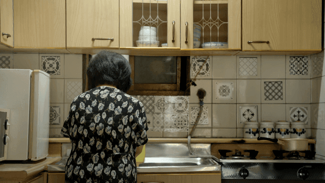 부엌에서 설거지를 하는 노인 여성의 뒷모습