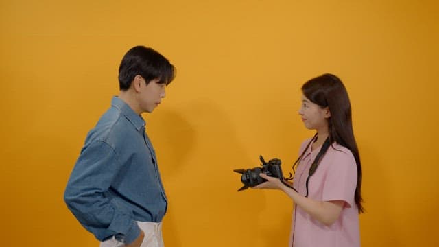 카메라로 남성 모델의 사진을 촬영하는 여성 사진작가