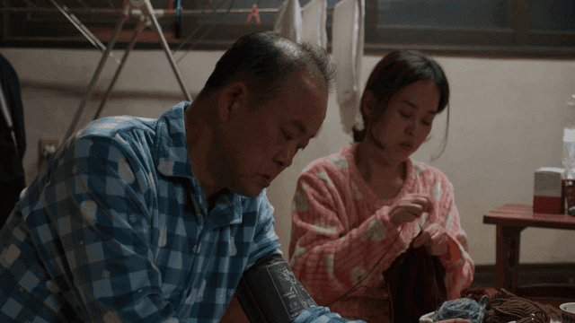 Husband checking blood pressure at home and wife knitting