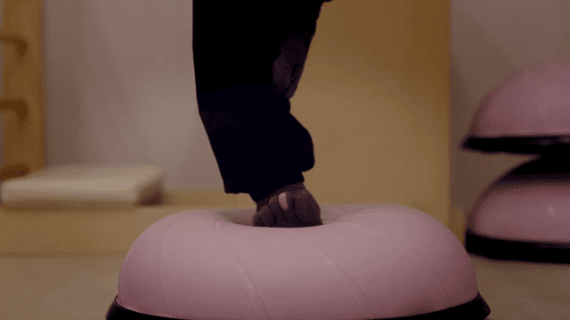 실내에서 핑크색 운동 볼 위에 균형 잡기