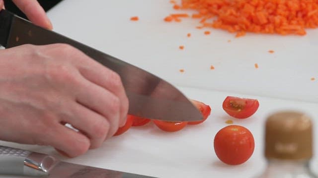 Slicing a Tomatos on a Cutting Board in the Kitchen