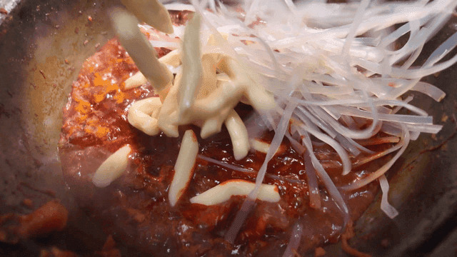 Spicy sauce poured over rice cakes and glass noodles