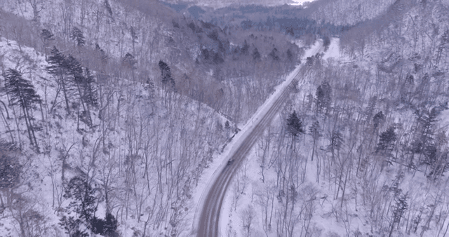 Remote road in snow-covered mountain with car