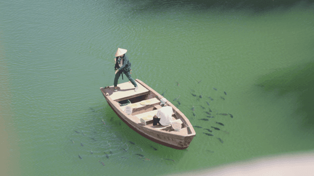 두 사람이 녹색 강에서 배를 타고 낚시하는 모습