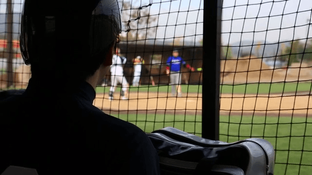 Baseball player watching a game from the dugout