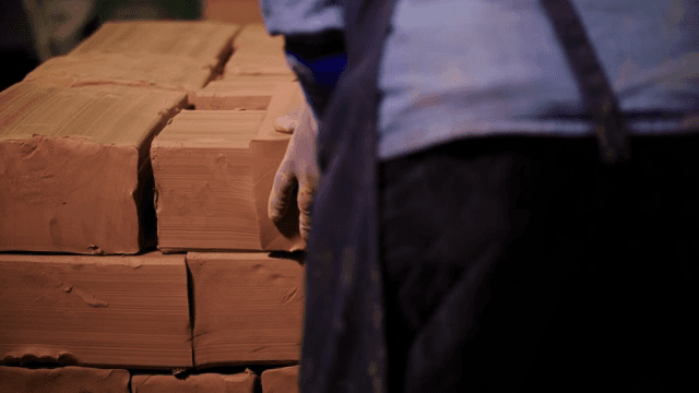 작업장에서 점토 블록을 쌓는 작업자