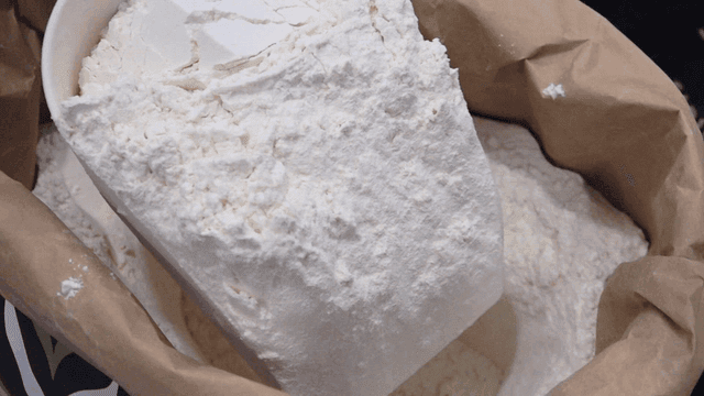 Scoop lifting flour from paper bag