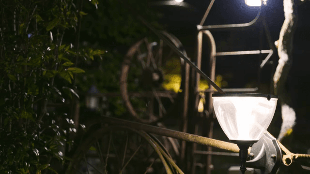 Rustic wheel and lamp in a garden at night