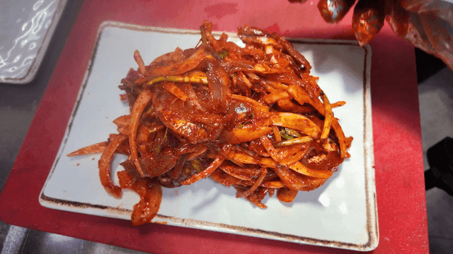 Spicy raw anchovy salad served on white plate