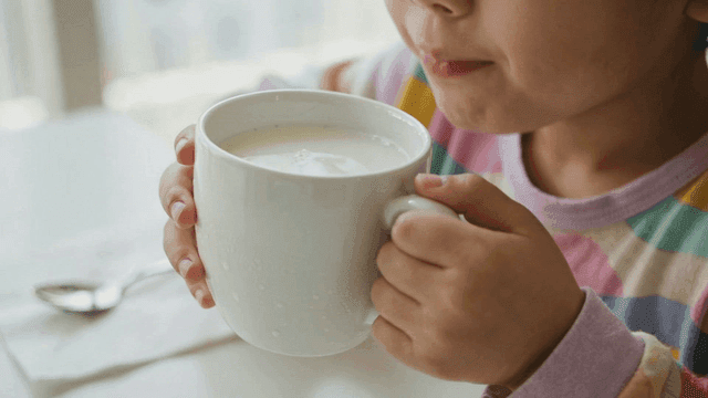 Child drinking milk from a large cup