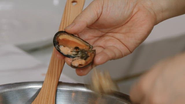 Putting rice between mussels with a spoon