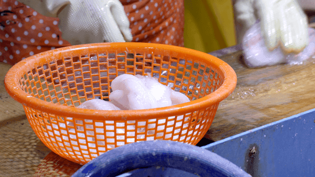 Person cleaning fish on wooden cutting board
