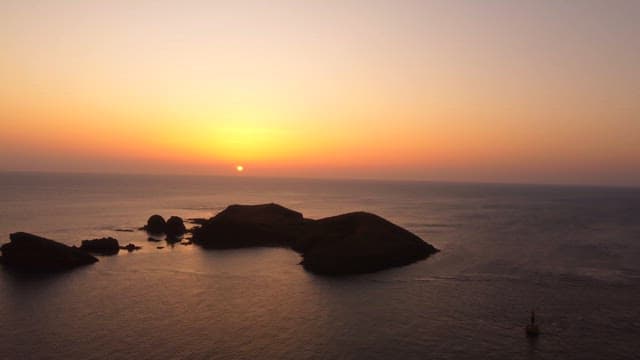 섬이 있는 고요한 바다 위의 일몰