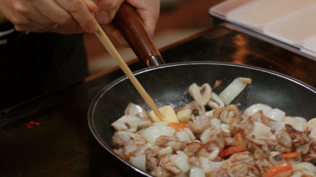 Cooking stir-fried vegetables and meat in a frying pan indoors