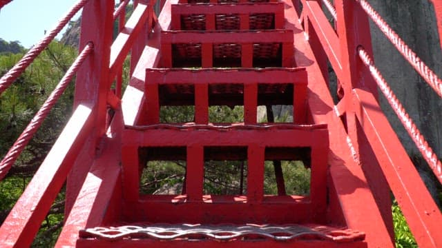 Red stairs on a mountain covered with green trees