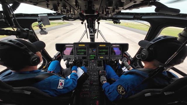 Two pilots inside a helicopter cockpit preparing for takeoff