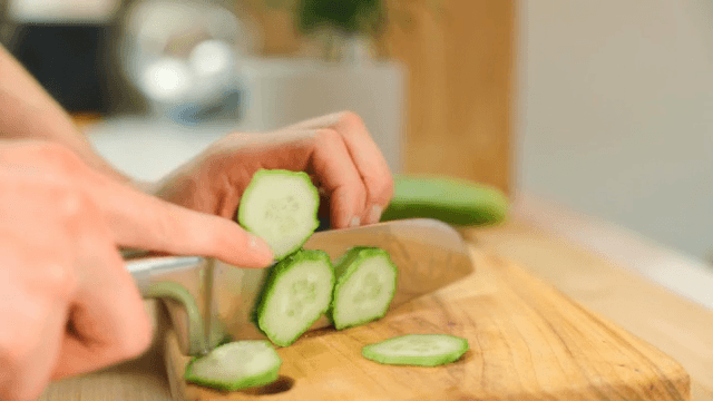 나무 도마 위에서 신선한 오이 자르기