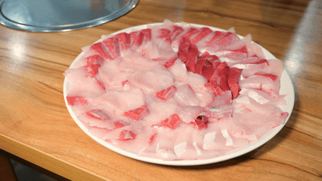 Plate of fresh yellowtail sashimi on wooden table