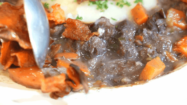 Beef Bourguignon scooped out with spoon