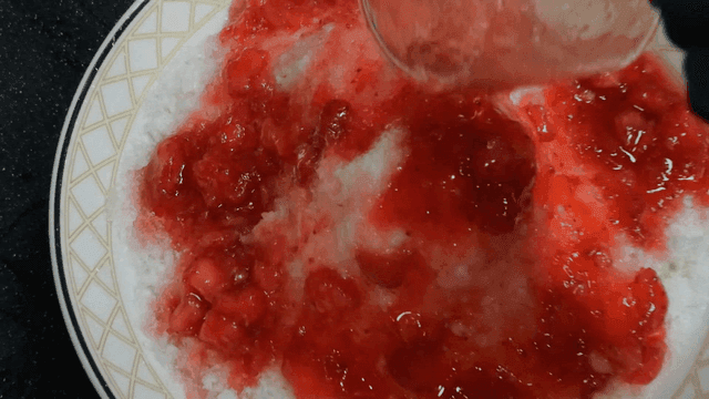 빙수 위에 딸기 시럽을 붓는 장면