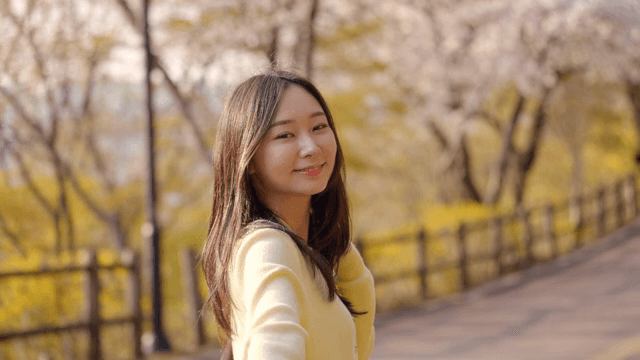 햇살이 비치는 공원 길을 걷는 여성