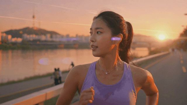 Woman jogging along riverbank at sunset