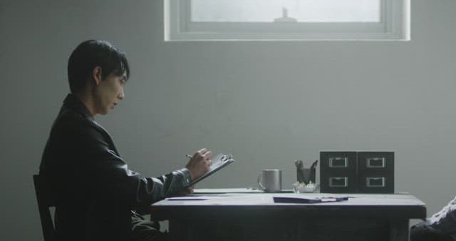 어두운 방에서 서류를 작성하는 남자