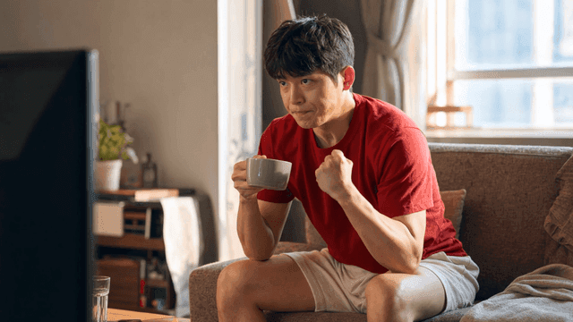 Man who watches TV and cheers while drinking coffee