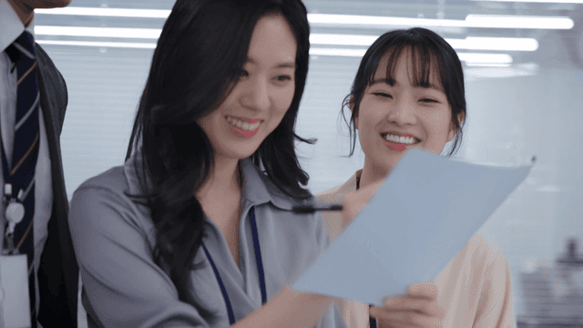 Team members standing and smiling while reviewing meeting documents