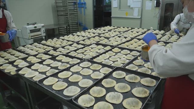 Bread dough being brushed with egg wash in a bakery kitchen