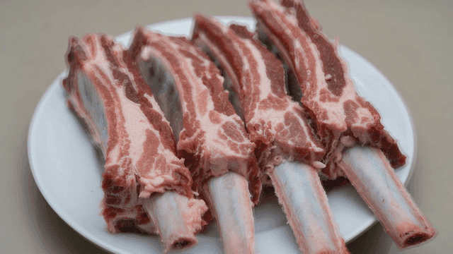 Raw beef ribs on a white plate