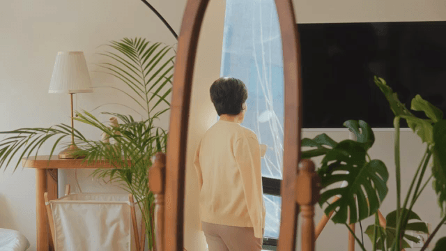 거울에 비친 창가에 서 있는 여성