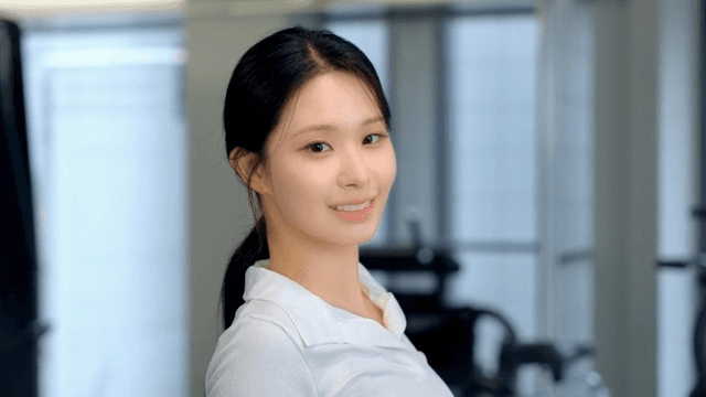 묶은 머리를 정리하고 뒤를 보며 미소짓는 젊은 여성