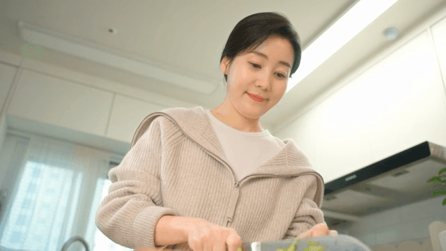 부엌에서 채소를 썰고 있는 여성