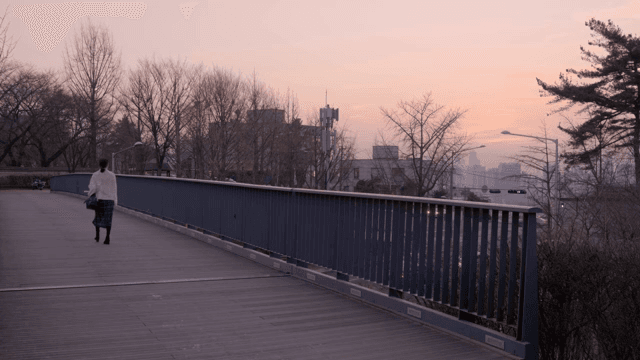해질녘 다리 위를 걷는 여성