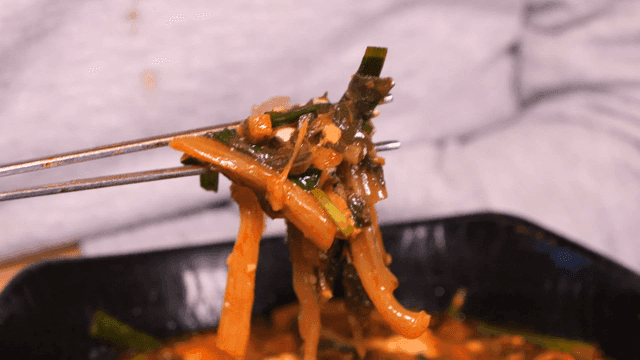 Person scooping up soft tofu jjambbong shiraegi with chopsticks