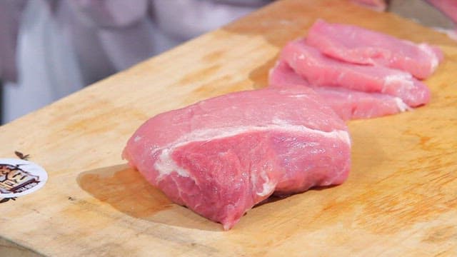 Slicing fresh pork on a wooden board