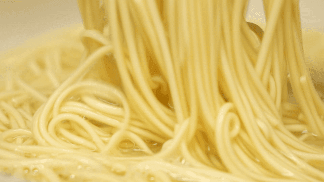 Yellow pasta noodles cooking in pasta water