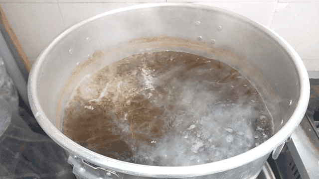 Broth in large pot boiling on stove.