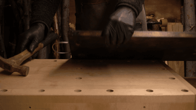 망치로 금속 와이어를 나무 판에 고정하는 장인