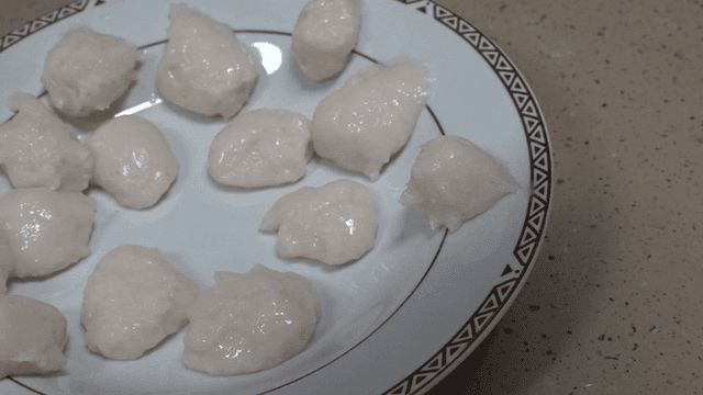 Plate with white fish balls on table