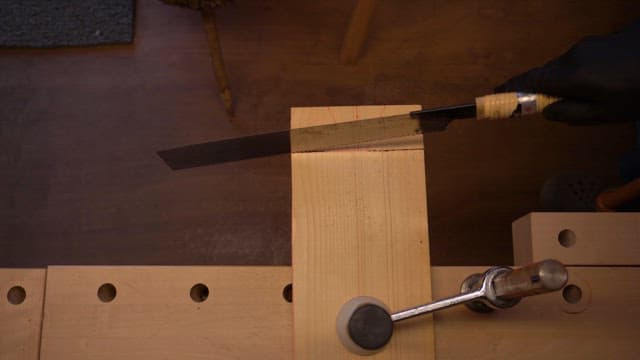 Wood being cut with a saw on a workbench