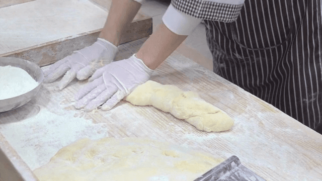 밀가루 위에서 반죽을 하는 제빵사