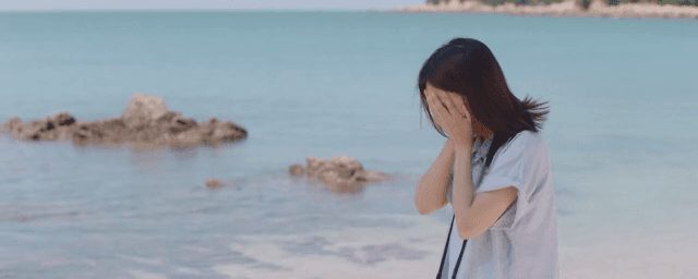 Woman standing in front of the sea and holding back tears