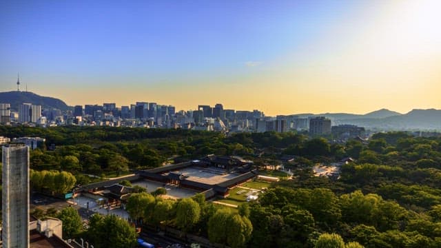 City skyline transitioning from day to night with traditional architecture in the foreground