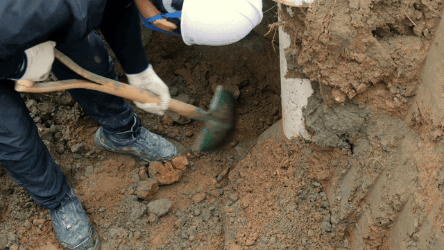 파이프 근처에서 흙을 파는 작업자