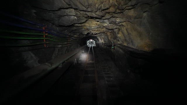 Narrow and dark mine tunnel with safety warning signs