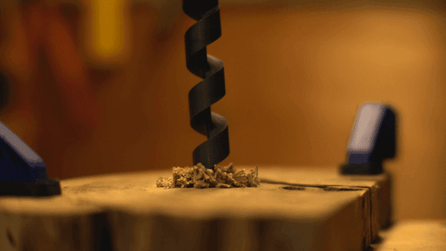 드릴 비트가 나무 표면을 뚫는 장면