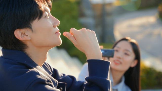 공원에서 캠코더로 영상을 찍는 커플