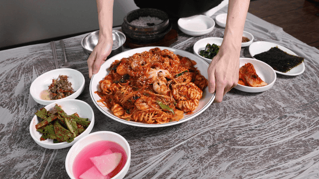 Table with Korean side dishes and spicy seafood stew